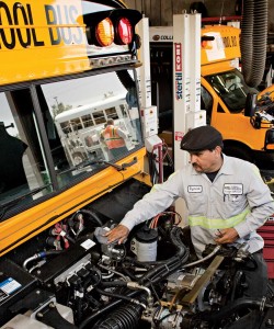 A photo of a mechanic working on a propane powered bus.