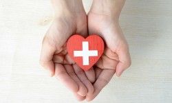 A photo of hands holding a crafted heart with the medic cross symbol.